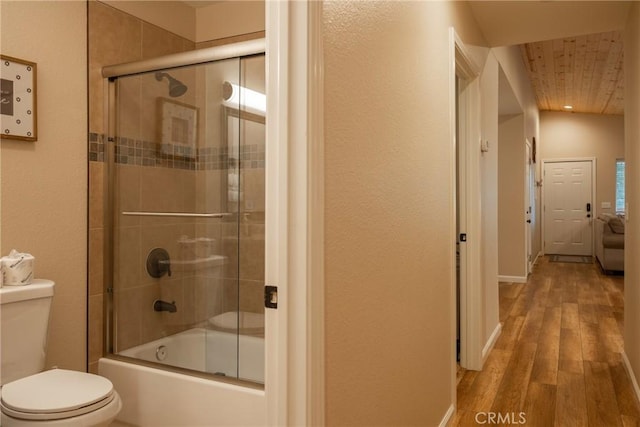 bathroom featuring toilet, wood-type flooring, wood ceiling, and combined bath / shower with glass door