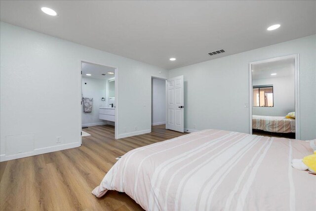 bedroom with connected bathroom and light hardwood / wood-style floors