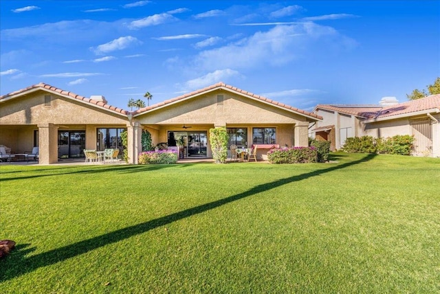 back of property with ceiling fan, a lawn, and a patio