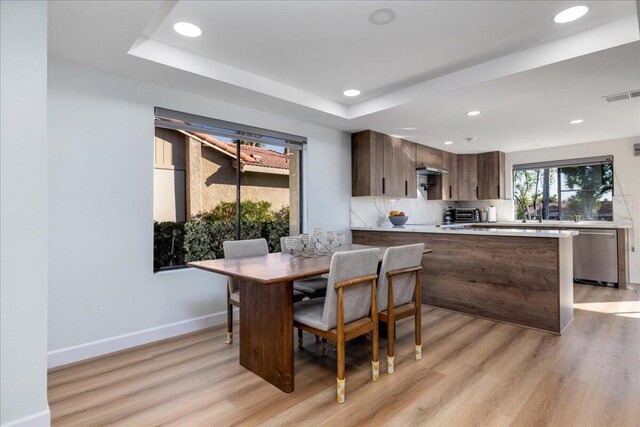 dining space featuring light wood-type flooring and a tray ceiling