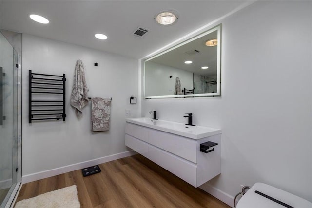 bathroom with radiator, a shower with door, wood-type flooring, and vanity