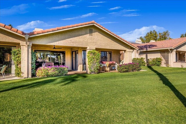 rear view of property featuring ceiling fan and a lawn