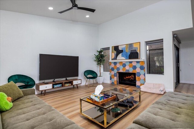 living room with ceiling fan, hardwood / wood-style flooring, and a tile fireplace