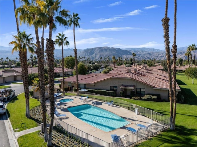 view of swimming pool featuring a lawn, a mountain view, and a patio