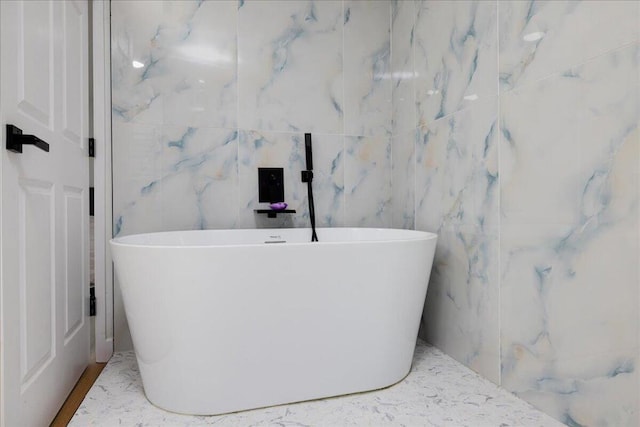 bathroom featuring tile walls and a tub to relax in