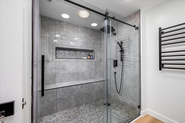 bathroom with hardwood / wood-style flooring, an enclosed shower, and radiator heating unit