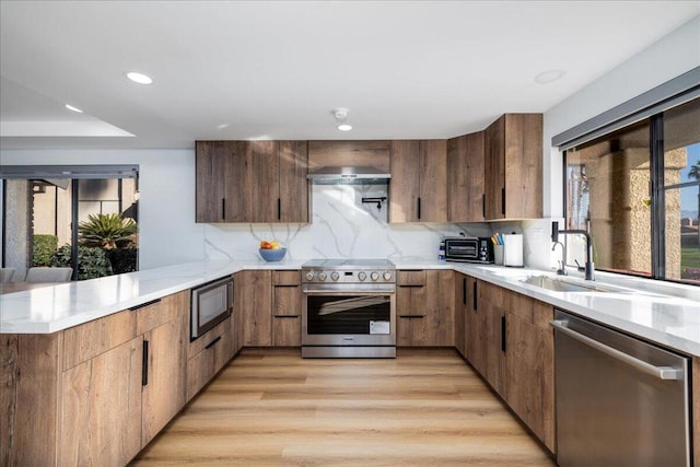 kitchen featuring plenty of natural light, appliances with stainless steel finishes, decorative backsplash, and kitchen peninsula