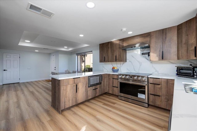 kitchen featuring light hardwood / wood-style floors, kitchen peninsula, decorative backsplash, built in microwave, and stainless steel electric range