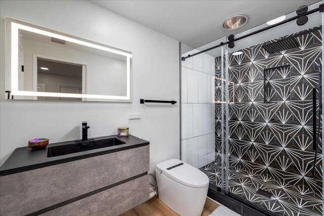 bathroom featuring toilet, a shower with shower door, hardwood / wood-style floors, and vanity