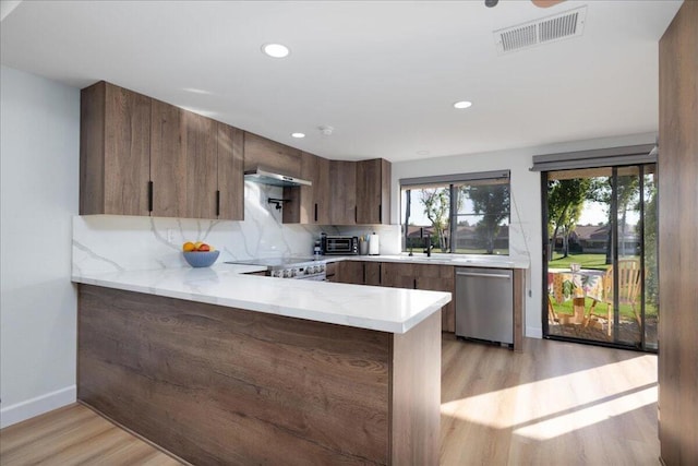 kitchen with tasteful backsplash, dishwasher, light hardwood / wood-style floors, stove, and kitchen peninsula