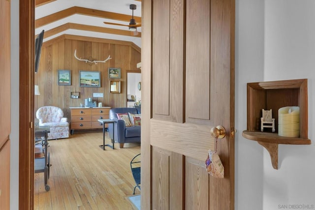 hallway featuring vaulted ceiling, wooden walls, and light wood-type flooring