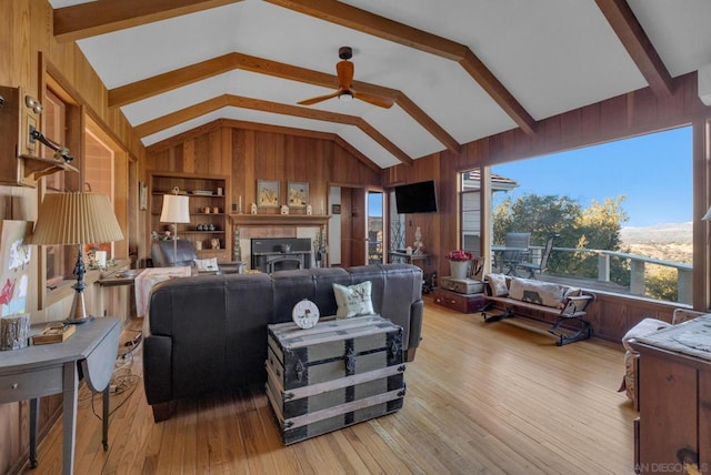 living room with ceiling fan, built in shelves, lofted ceiling with beams, and light wood-type flooring