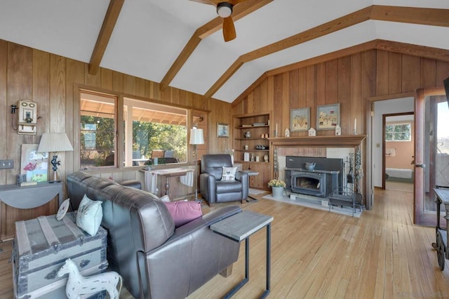 living room featuring built in shelves, a fireplace, lofted ceiling with beams, light wood-type flooring, and ceiling fan