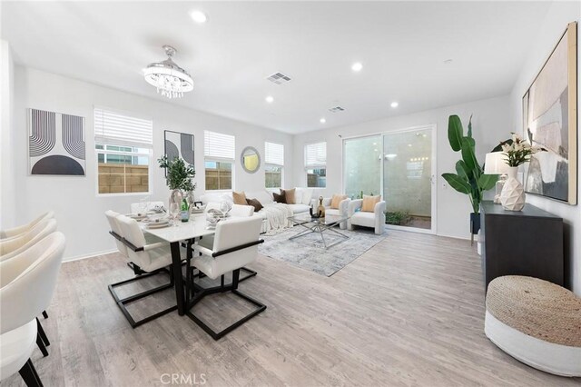 dining area with light hardwood / wood-style floors and a notable chandelier