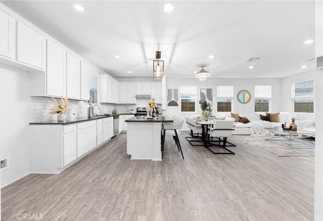 kitchen with a center island, white cabinetry, light hardwood / wood-style flooring, a healthy amount of sunlight, and appliances with stainless steel finishes