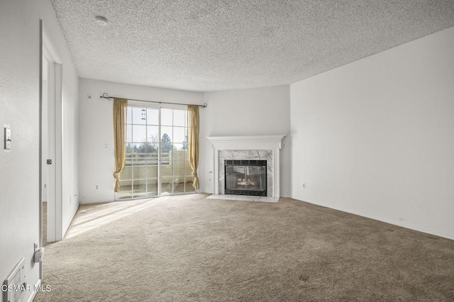 unfurnished living room featuring a premium fireplace, a textured ceiling, and carpet flooring