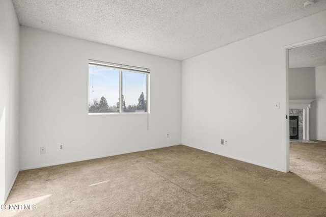 empty room with a fireplace, a textured ceiling, and carpet flooring