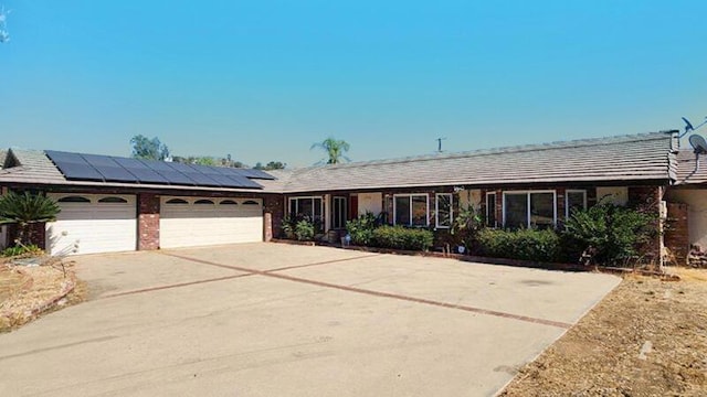 ranch-style home with a garage and solar panels