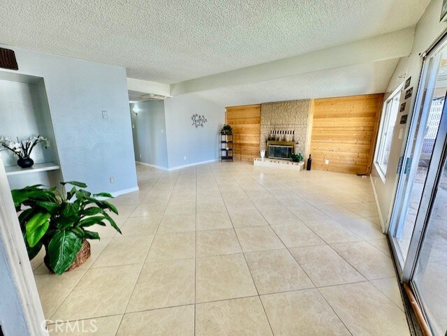 living room with light tile patterned flooring, a textured ceiling, wood walls, and a fireplace