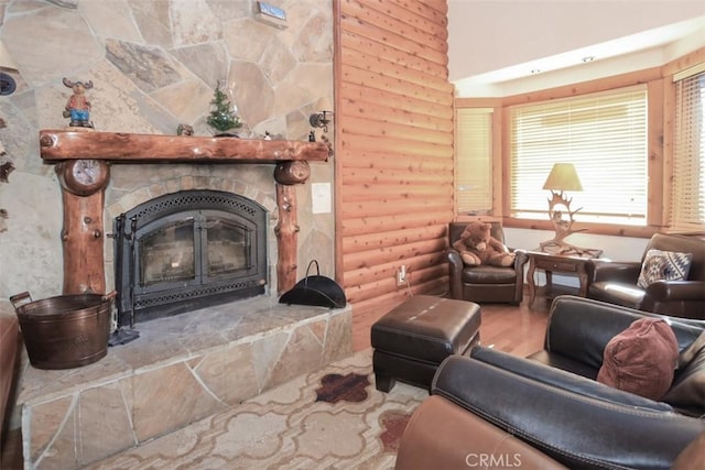 living room with log walls, hardwood / wood-style flooring, and a stone fireplace