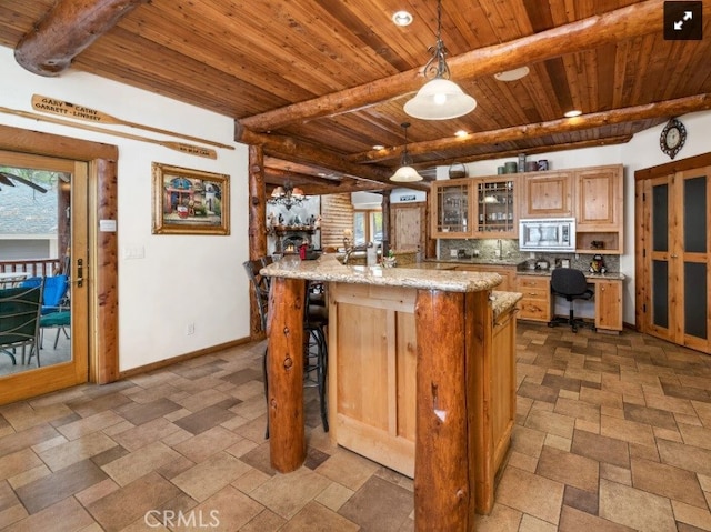 kitchen with stainless steel microwave, decorative light fixtures, beamed ceiling, wood ceiling, and light stone counters