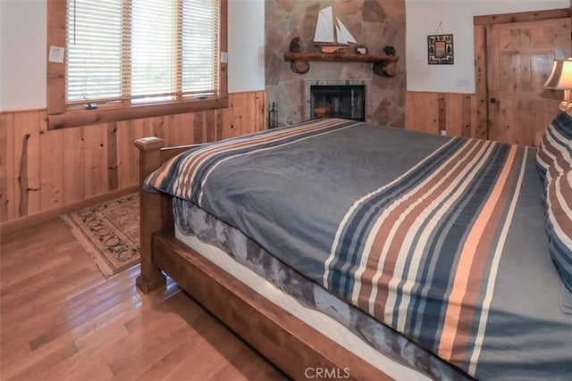 bedroom with a fireplace, wood walls, and light hardwood / wood-style floors