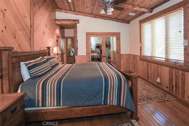 bedroom with wood ceiling, wood walls, hardwood / wood-style floors, ceiling fan, and vaulted ceiling with beams