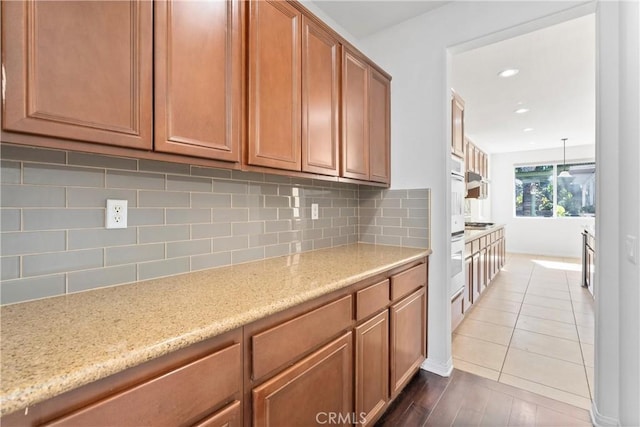 kitchen featuring decorative backsplash, light stone counters, and tile patterned floors