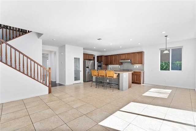 kitchen with tasteful backsplash, pendant lighting, a breakfast bar, an island with sink, and stainless steel appliances