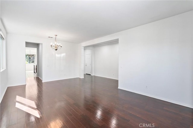 unfurnished room featuring a chandelier and dark hardwood / wood-style flooring