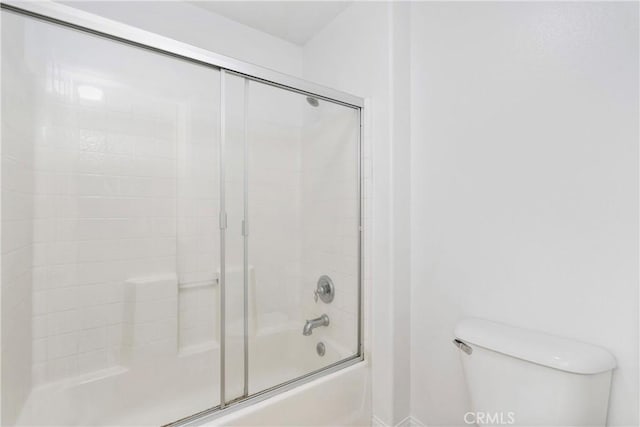 bathroom featuring toilet and bath / shower combo with glass door