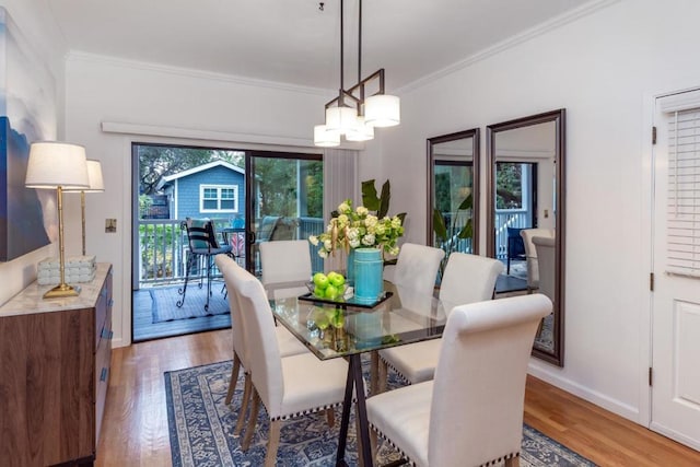 dining space with ornamental molding, wood-type flooring, and a chandelier