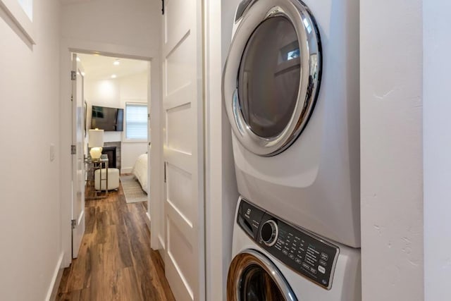 washroom with stacked washer / drying machine and dark hardwood / wood-style flooring