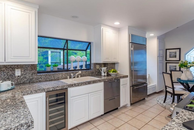 kitchen with high end fridge, sink, beverage cooler, decorative backsplash, and white cabinets