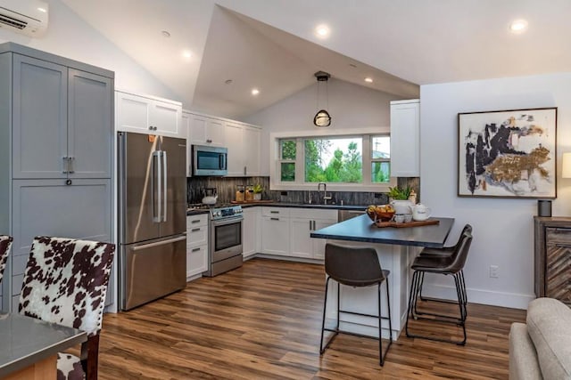 kitchen with sink, white cabinetry, hanging light fixtures, stainless steel appliances, and a wall mounted AC