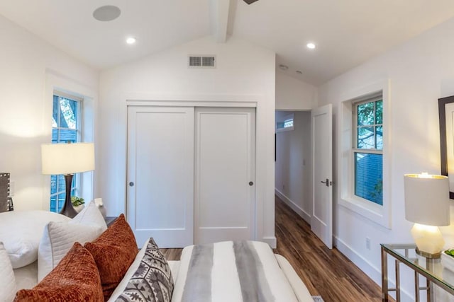 bedroom featuring dark hardwood / wood-style flooring, lofted ceiling with beams, and a closet