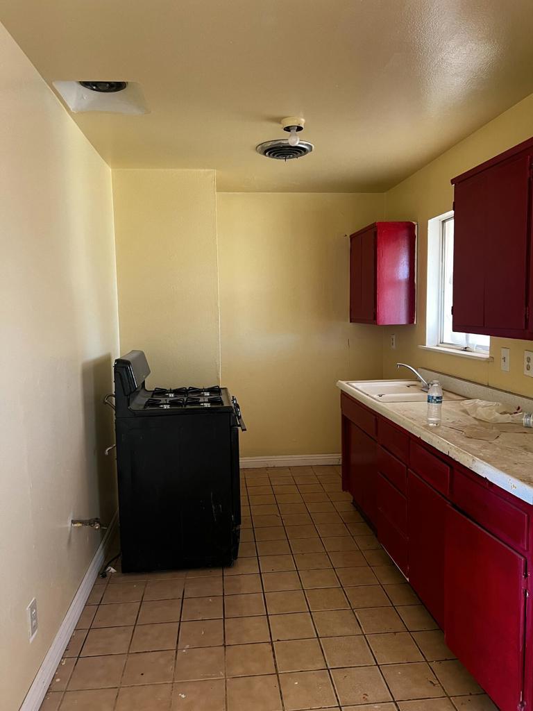 kitchen featuring light tile patterned floors, black stove, and sink