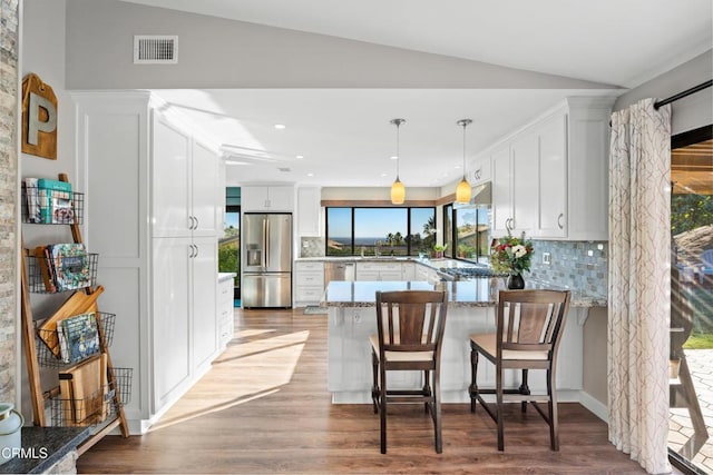 kitchen with kitchen peninsula, decorative backsplash, a wealth of natural light, appliances with stainless steel finishes, and white cabinetry