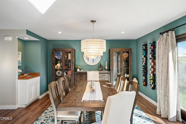 dining room featuring a notable chandelier, sink, and dark wood-type flooring