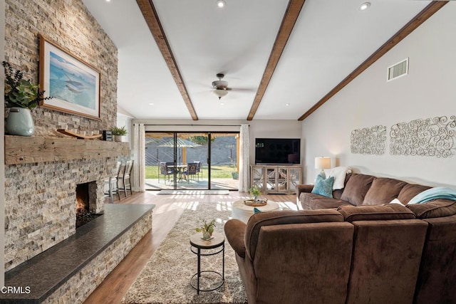 living room featuring ceiling fan, lofted ceiling with beams, a fireplace, and light hardwood / wood-style flooring