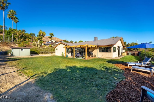 rear view of property with a lawn, a pergola, a patio area, and a storage unit