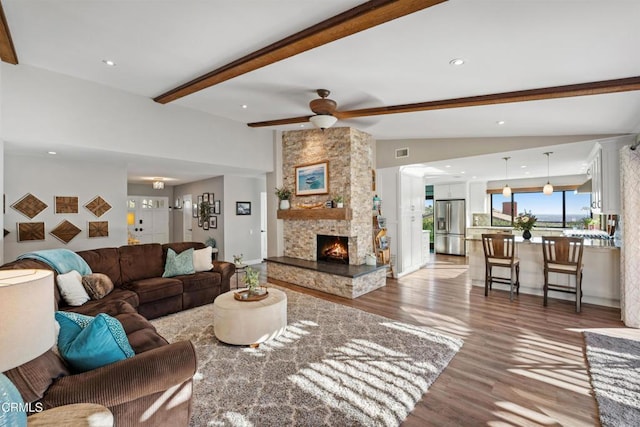 living room with hardwood / wood-style floors, ceiling fan, lofted ceiling with beams, and a fireplace