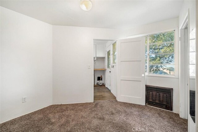 carpeted spare room featuring heating unit