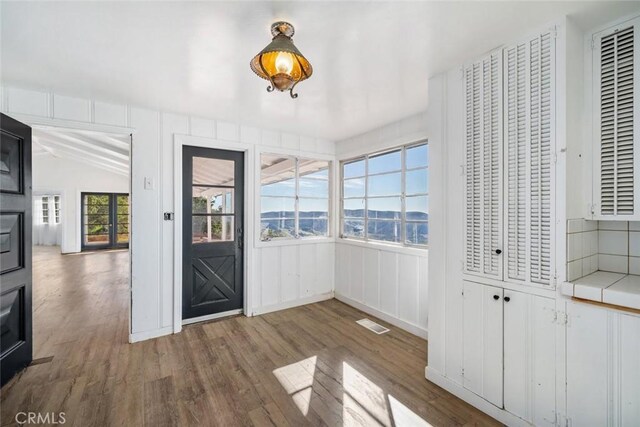 foyer featuring a healthy amount of sunlight, wood-type flooring, and vaulted ceiling