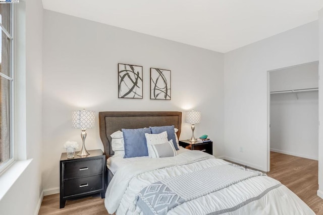 bedroom featuring a closet, a walk in closet, and light hardwood / wood-style floors