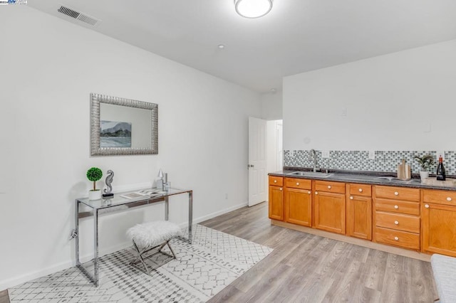 kitchen with tasteful backsplash, light wood-type flooring, and sink