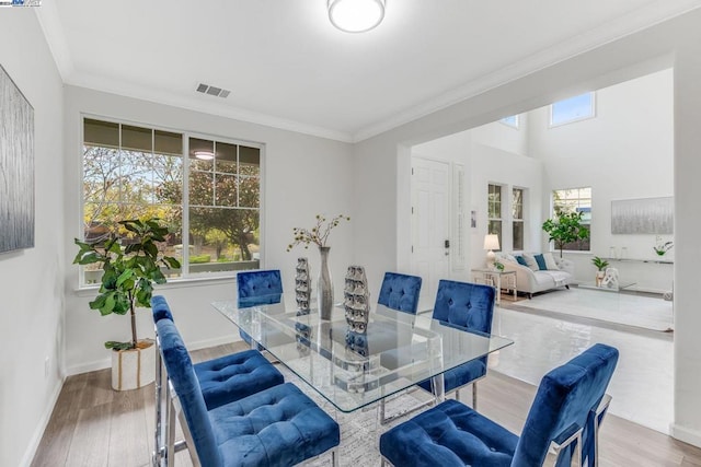 dining area with wood-type flooring and ornamental molding