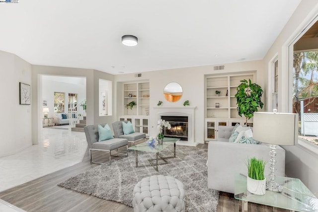 living room with built in features and hardwood / wood-style floors