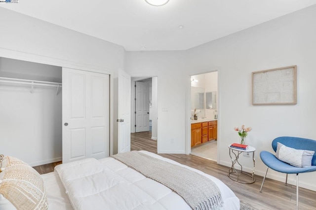 bedroom featuring a closet, ensuite bath, and light wood-type flooring