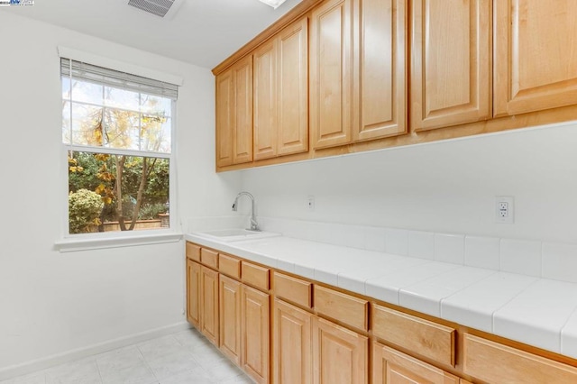 kitchen featuring tile counters, light brown cabinetry, plenty of natural light, and sink